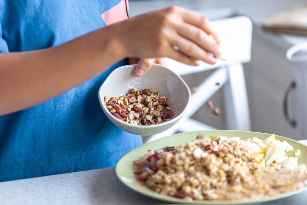 Why Make-Ahead Breakfast Bowls Are a Game-Changer 1 Bin Recipes woman prepares oatmeal with fruits closeup Bin Recipes